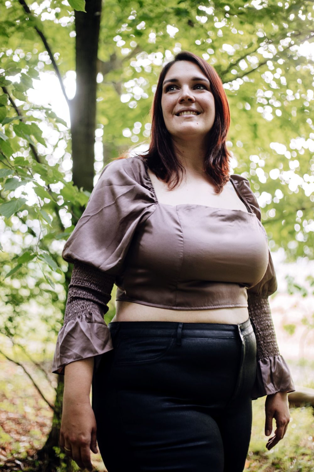 Frau steht im Wald und lächelt
